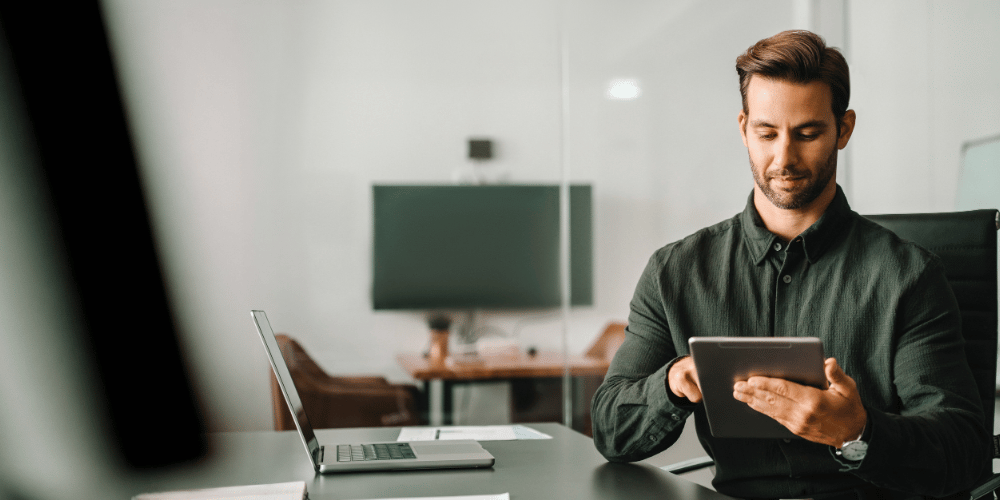 Executive professional man working online using computer for financial business banking work. European trade manager looking at digital tablet screen sitting at desk in office. Web banner, copy space