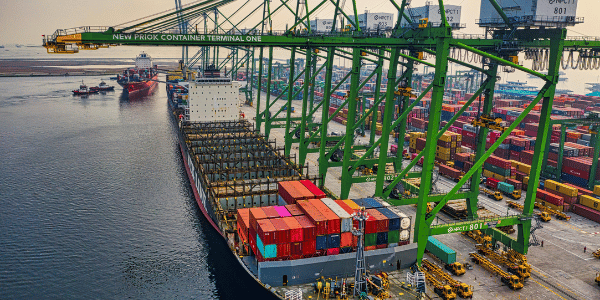 Un grand navire de transport de conteneurs à quai dans un terminal maritime moderne, illustrant les réseaux logistiques internationaux et les stratégies commerciales mondiales.
