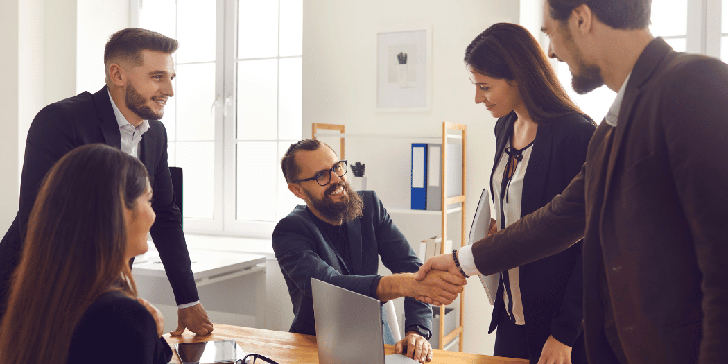 Business professionals shaking hands during a meeting to discuss an international expansion partnership.