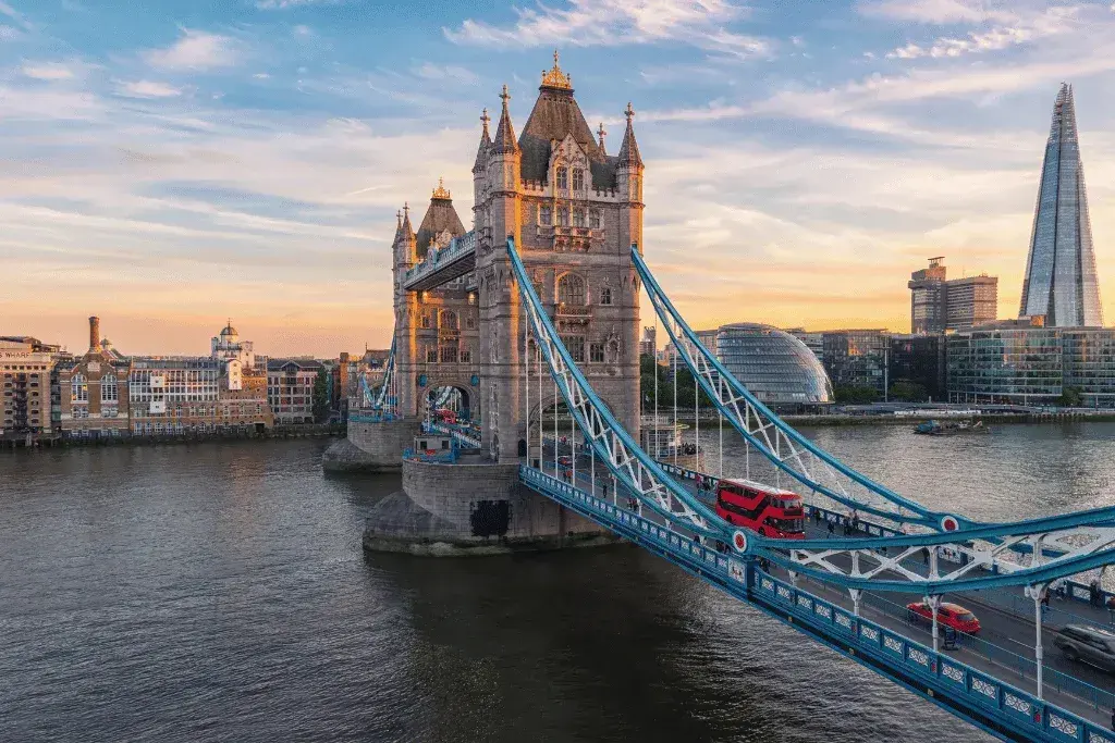 El Tower Bridge de Londres con un autobús rojo de dos pisos cruzando al atardecer.